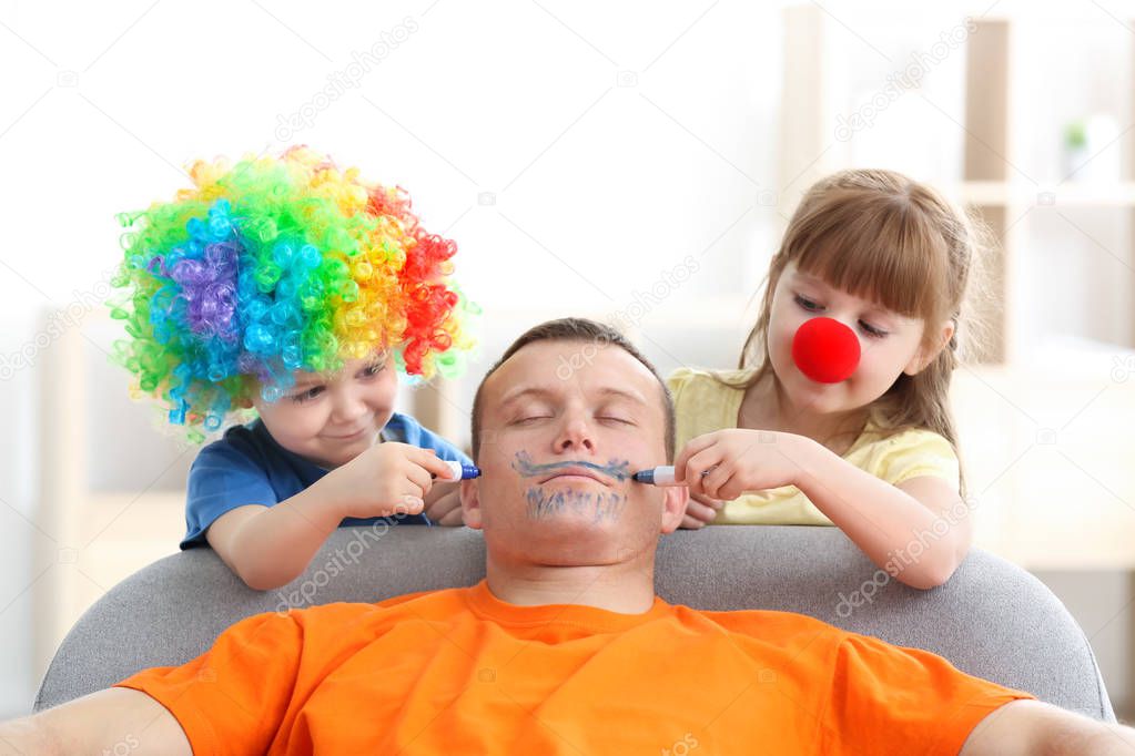 Little children painting their father's face while he sleeping. April fool's day prank