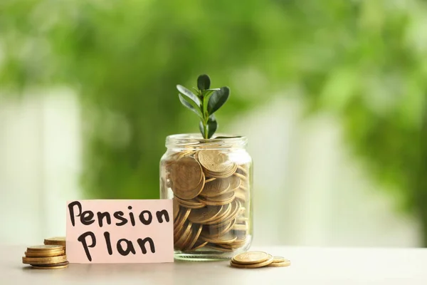 Plant growing from glass jar with coins on table against blurred background. Pension planning concept — Stock Photo, Image