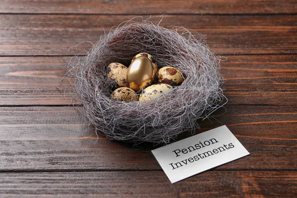 Nest with eggs and sign PENSION INVESTMENTS on wooden background — Stock Photo, Image