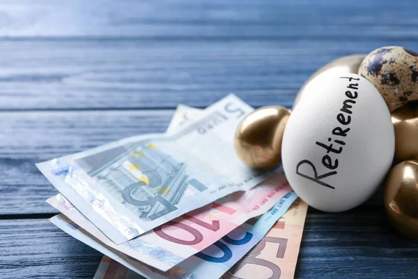 Egg with word RETIREMENT and money on table. Pension planning