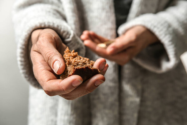 Poor woman holding piece of bread and coins, closeup