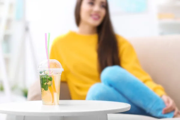 Copa con sabrosa limonada refrescante y mujer borrosa en el fondo — Foto de Stock