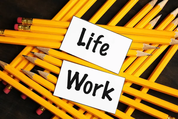 Words LIFE, WORK and many pencils on table