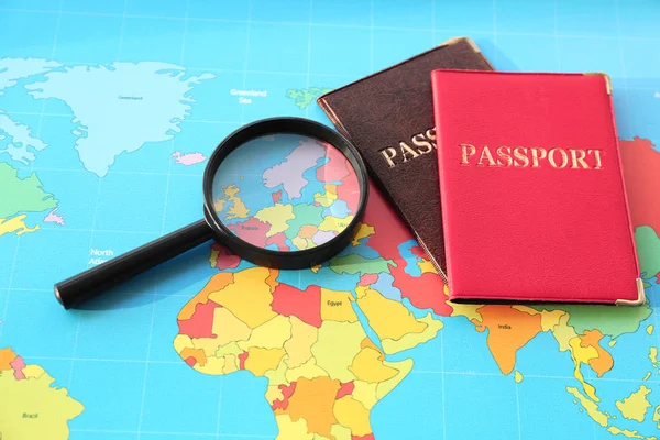 Μεγεθυντικό φακό, διαβατήρια σε παγκόσμιο χάρτη. Έννοια της μετανάστευσης — Φωτογραφία Αρχείου