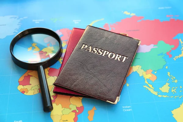 Magnifying glass, passports on world map. Immigration concept — Stock Photo, Image