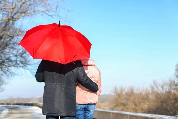 Unga romantiska par med ljusa paraply gå på solig vinterdag — Stockfoto
