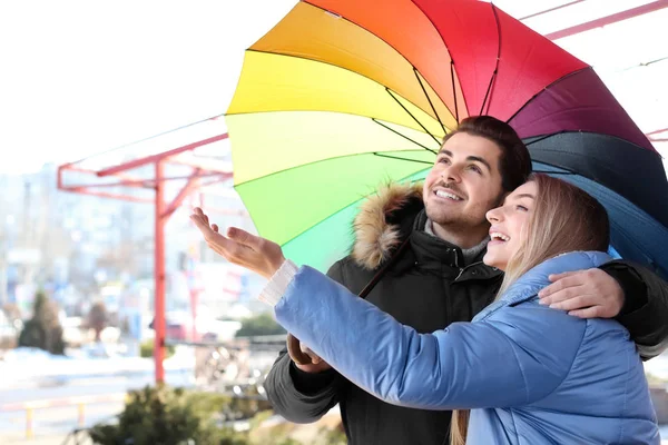 Jovem casal romântico com guarda-chuva colorido ao ar livre — Fotografia de Stock