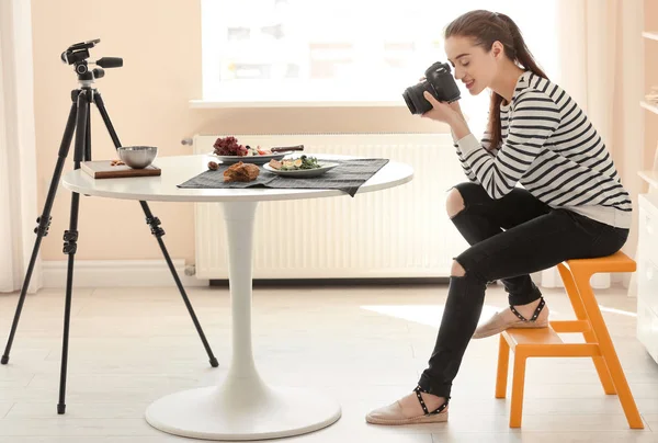Молода жінка з професійною камерою знімає натюрморт у приміщенні — стокове фото