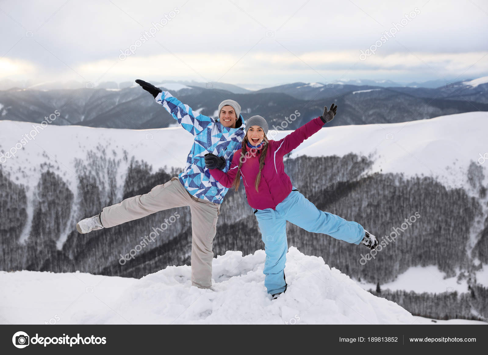 Happy couple having fun on snowy mountain peak at resort