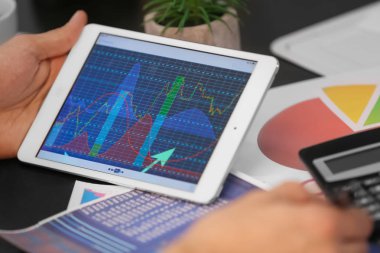 Hisse senedi grafiği veri masada ekranda tablet bilgisayar kullanan adam