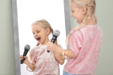 Mikrofon kapalı aynanın önünde poz ile sevimli küçük kız