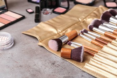 Profesyonel makyaj sanatçısı gri masada Dekoratif kozmetik ile fırçalar
