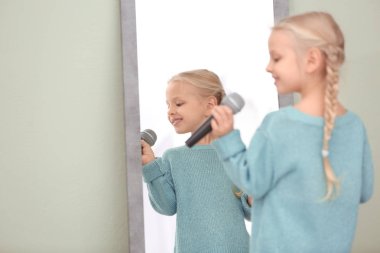 Mikrofon kapalı aynanın önünde poz ile sevimli küçük kız