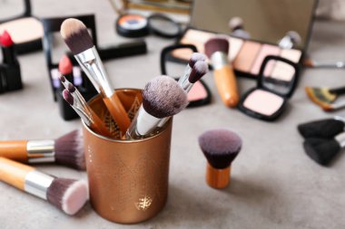 Profesyonel makyaj sanatçısı gri masada Dekoratif kozmetik ile fırçalar