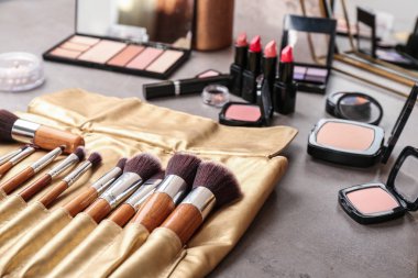 Profesyonel makyaj sanatçısı gri masada Dekoratif kozmetik ile fırçalar