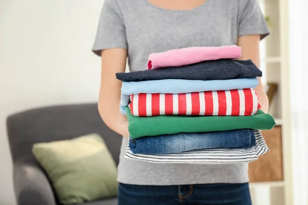 Mujer sosteniendo una pila de ropa limpia en el interior. Día de lavandería — Foto de Stock