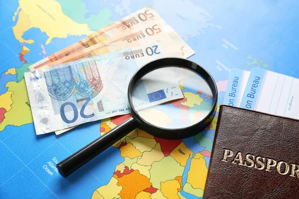Passport, money and magnifying glass on map
