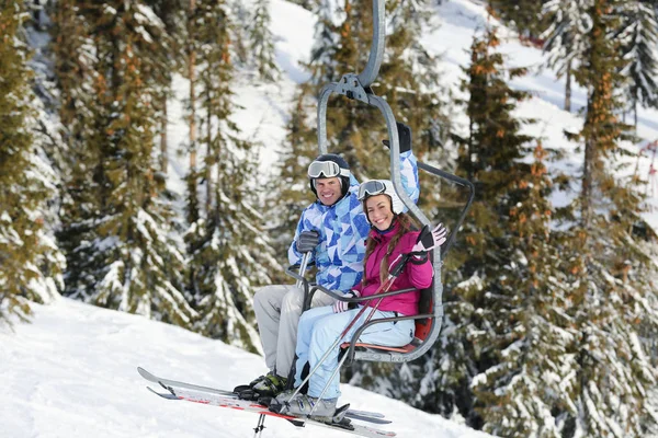 Happy couple on ski lift at snowy resort. Winter vacation — Stock Photo, Image