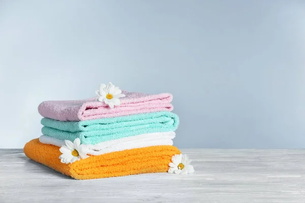 一叠干净的毛巾, 桌子上有花, 灰色的背景。洗衣日 — 图库照片