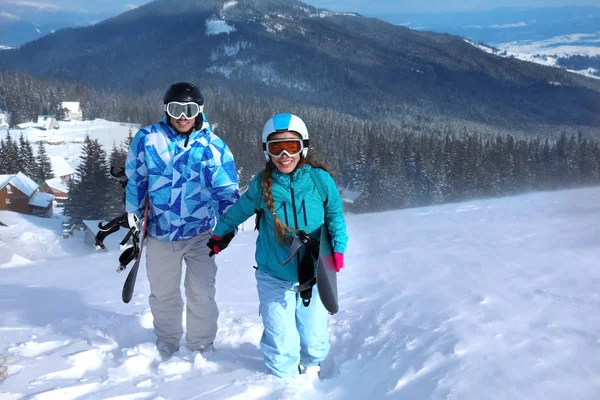Casal com snowboards em pista de esqui no resort nevado. Férias inverno — Fotografia de Stock