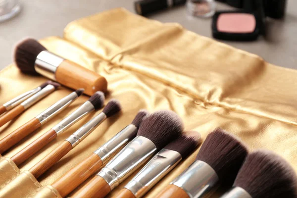 Close up of brushes of professional makeup artist in leather case on table