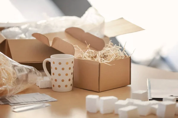 Open parcel box with cup on table in home office