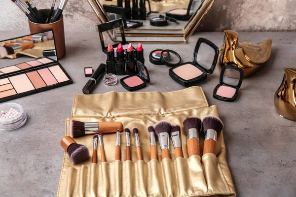 Dekoratif kozmetik ve profesyonel makyaj sanatçısı gri masada fırçalar