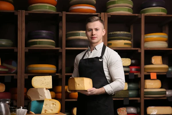 Young worker holding cheese in shop — Stock Photo, Image