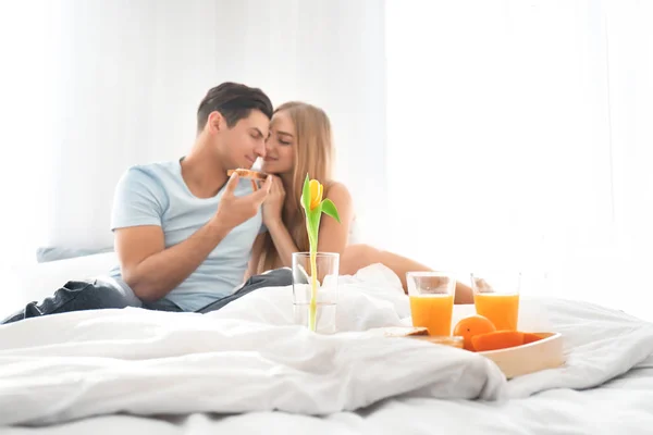 ベッドで朝食を持っている若い素敵なカップル — ストック写真