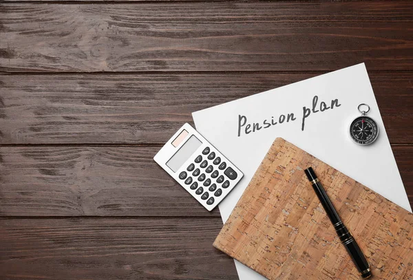 Paper sheet with text PENSION PLAN, calculator and notebook on wooden table