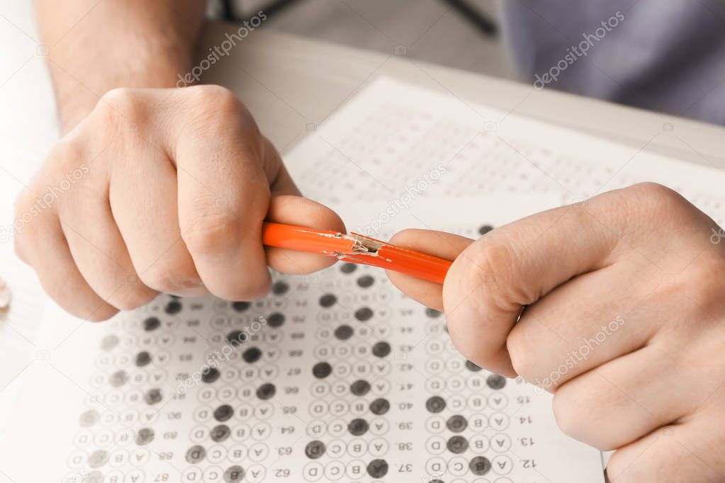 Close up of hands of nervous student breaking pencil while passing exam