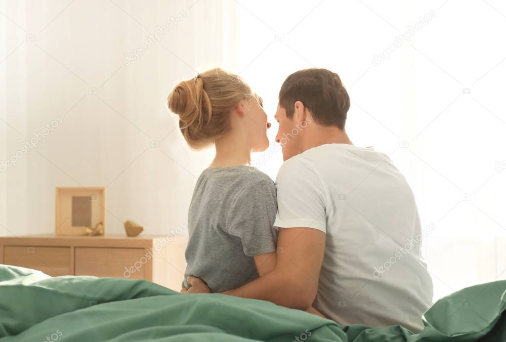 Young lovely couple sitting on bed at home