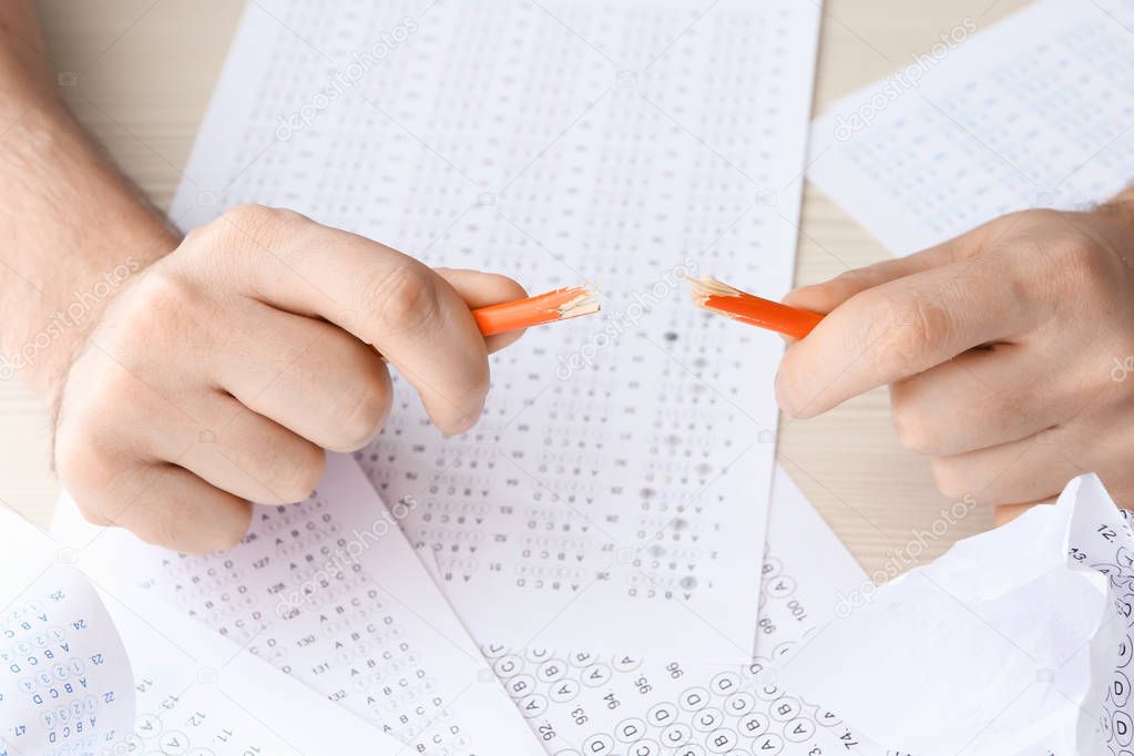 Close up of hands of nervous student breaking pencil while passing exam