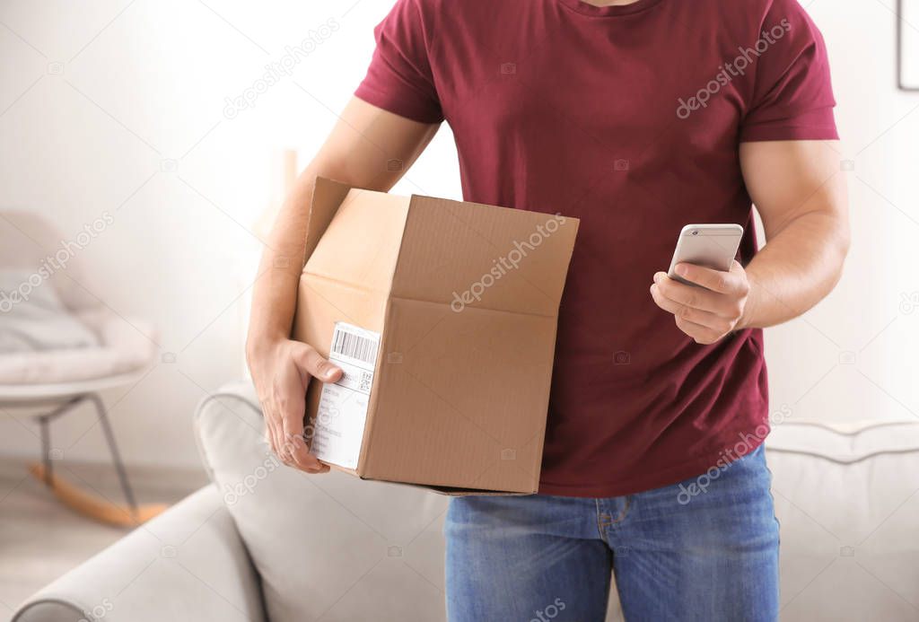 Young man making call about delivered parcel at home