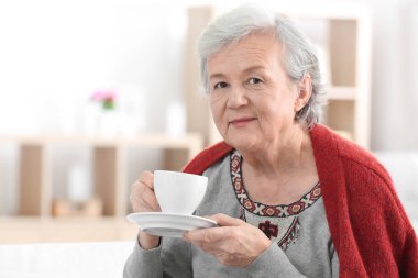 İşitme cihazı kapalı çay içme ile olgun kadın