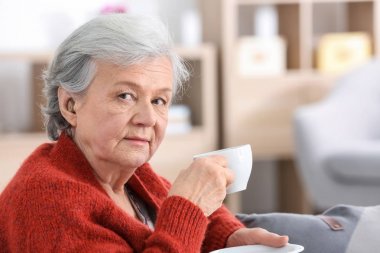 İşitme cihazı kapalı çay içme ile olgun kadın