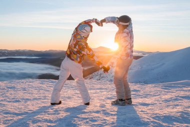 Güzel çift karlı tepe üzerinde kalp şeklinde günbatımında ellerimi. Kış tatili