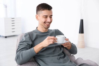 Koltukta oturan ve kahve tutan genç adam