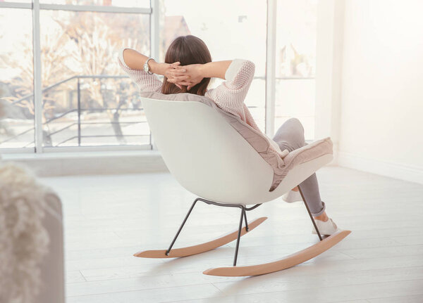 Young woman resting in armchair in light room