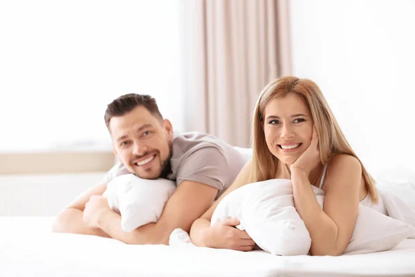 年轻夫妇躺在床上与软枕头在家里 — 图库照片