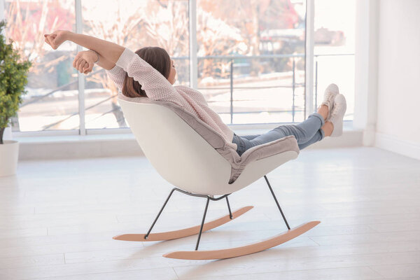 Young woman resting in armchair in light room