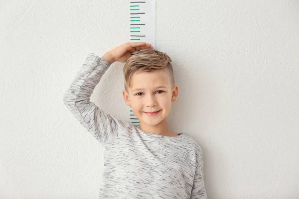 little boy measuring height near light wall