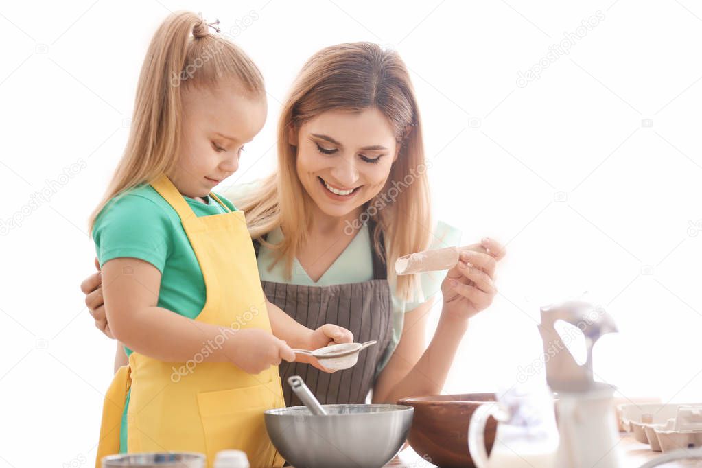 Mother with daughter sifting flour on kitchen