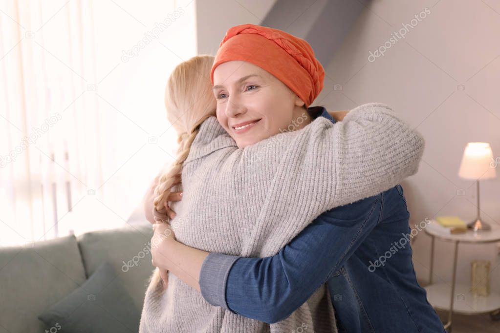 Young woman with cancer hugging her mother indoors