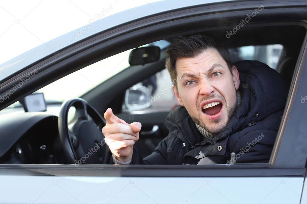 Emotional young man inside car in traffic jam