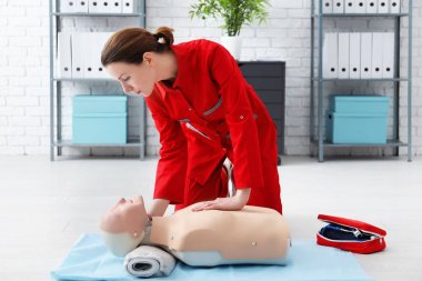 Woman practicing CPR on mannequin at first aid class clipart