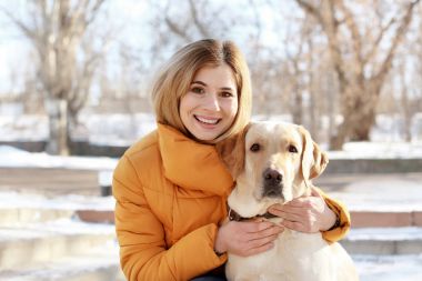 Kadın kucaklama sevimli köpek kış günü açık havada. Evde beslenen hayvan ve sahibi arasındaki dostluk