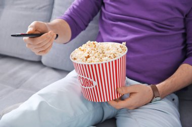 Genç adam evde kanepede televizyon izlerken