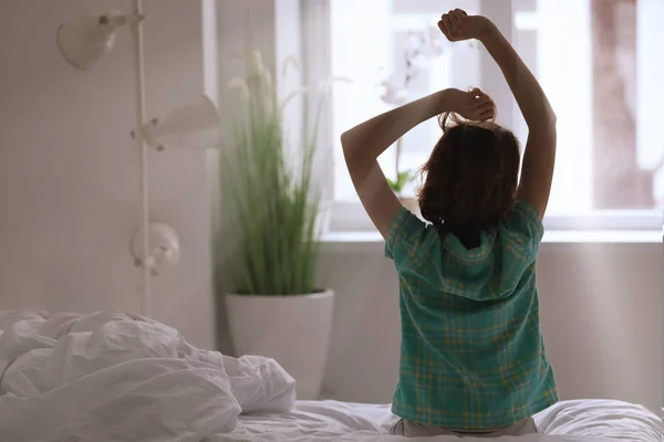 Mattina di donna che si allunga mentre si siede sul letto — Foto Stock