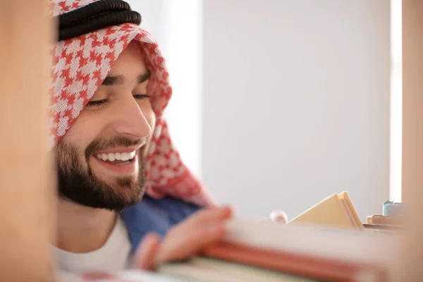Estudante muçulmano escolhendo livro de prateleira na biblioteca — Fotografia de Stock